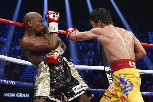 Floyd Mayweather has one of the most distinctive boxing styles. In this image, he leans back with a shoulder and a hand up to protect the head.